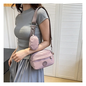 Detail of lavender nylon shoulder bag featuring an adjustable strap and small round pouch
