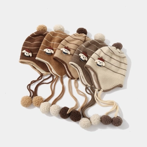 Flat lay detail showing five striped knit earflap hats with pom-poms and puppy patches