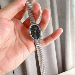 Detailed close-up of small oval women's quartz watch with silver metal stretch band