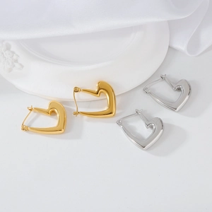 Gros plan de boucles d'oreilles cœur en or et argent sur un tissu en satin blanc élégant