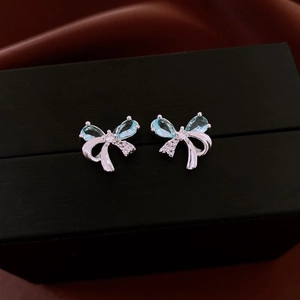 Macro shot of silver bow earrings with light blue teardrop gemstone and crystals