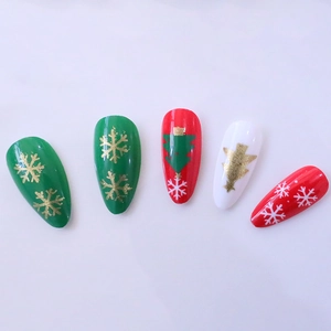 Long almond press-on nails with Christmas tree and snowflake designs in red, green and white