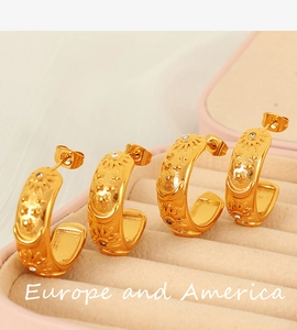 Detailed view of four golden C-shaped earrings with sun moon and star relief and zircon stones