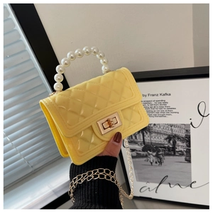 Close-up of yellow quilted jelly bag with pearl handle and golden chain details