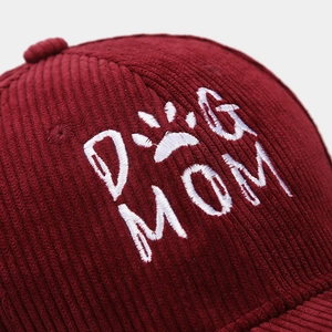 Close-up of white DOG MOM embroidery and paw print on wine red corduroy baseball cap