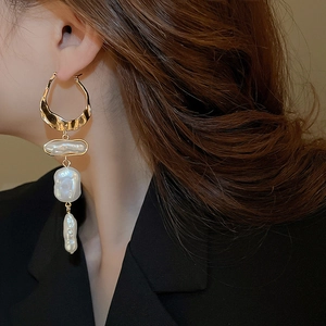 Detail of elegant gold hoop earrings with cascading baroque pearls on a professional model