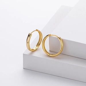 Close-up of S925 hallmark on polished gold hoop earrings in a minimalist scene