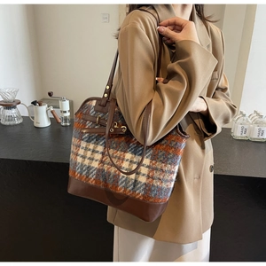 Detail of checkered tote bag with orange and blue pattern and brown leather handle