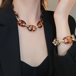 Dettaglio del set collana e bracciale con stampa leopardata indossato su un blazer nero