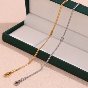 Detail of gold and silver snake chain bracelets with knot charm on green gift box