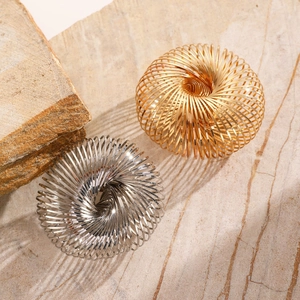 Detail of spiral woven metal bracelets in gold and silver finish on stone texture