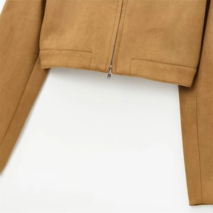 Détail d'une veste en daim beige avec texture mate et fermeture éclair en métal argenté