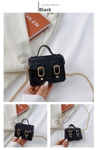 Detail of black patent leather satchel with magnetic snap and gold chain shoulder strap