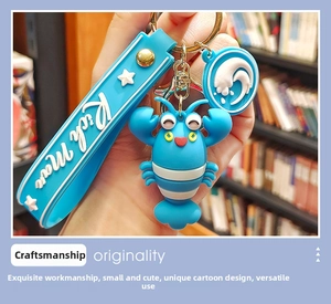 Close-up of blue cartoon lobster keychain with Rich Man strap and star pendant accessory