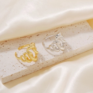 Irregular sculptural gold and silver plated 18k rings displayed on a stone surface