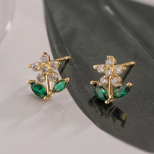 Gold flower earrings with clear and green marquise zircons in a balanced macro shot