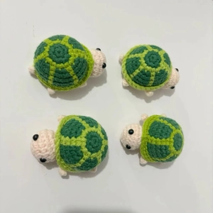 Close-up of four handmade crochet turtles showing detailed green yarn texture