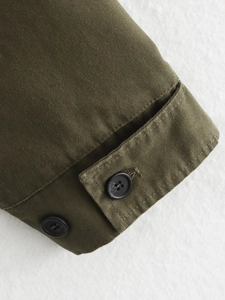 Close-up of military green jacket cuff with black buttons on twill canvas fabric