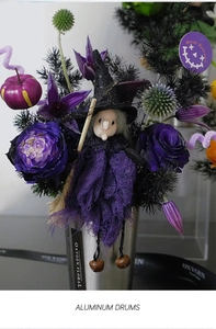 Close-up of Halloween witch doll with purple roses in a silver aluminum drum base