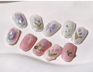 Macro shot of 3D butterfly charms and hand-painted tulips on French pink press-on nails