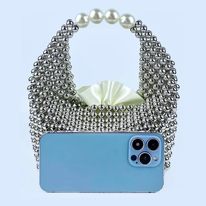 Detailed view of silver beaded pillow bag with pearl handle and smartphone for size scale