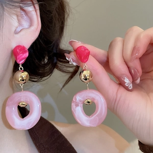 Detail of pink marble acrylic earrings and matching jewelry worn by a model