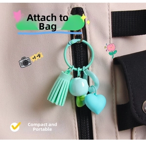 Close-up of mint green tulip keychain with tassel and heart pendant on a backpack