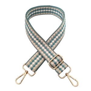 Close-up of geometric jacquard bag strap with gold metal hooks and adjustable buckle