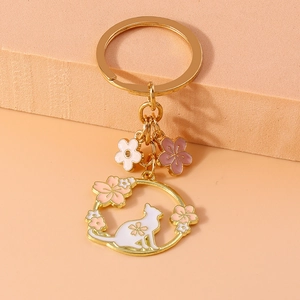 Detailed view of golden metal keychain featuring pink enamel cherry blossoms and cat charm