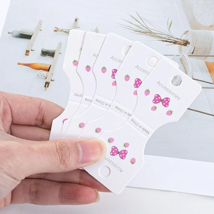 Stack of white jewelry display cards with strawberry and bow patterns for accessories