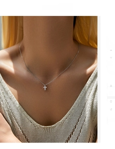 Close-up of a silver cross pendant with sparkling stones on a delicate O-chain