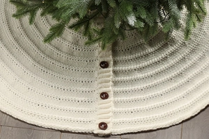 Close-up of cream knitted Christmas tree skirt featuring three brown vintage buttons