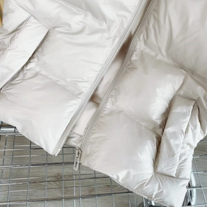 Detail der cremeweißen Steppweste mit Reißverschluss und wattiertem Baumwollstoff