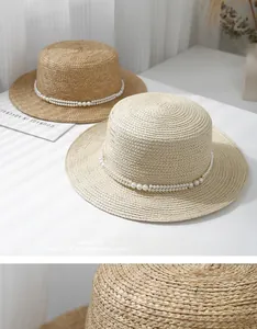 Detail of straw hats with flat tops and elegant double-row pearl chain decorations