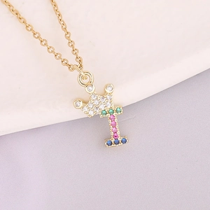Macro detail of 18K gold necklace crown and letter I pendant with colorful zircon stones