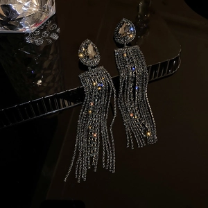 Detailed close-up of luxurious drop earrings featuring silver tassels and sparkling crystals