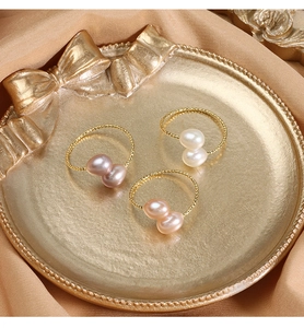 Three-color natural pearl rings with gold twisted bands on a luxury satin display tray