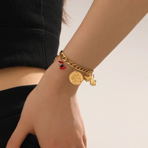 Detail of gold charm bracelet with insect motifs and stones worn on woman wrist