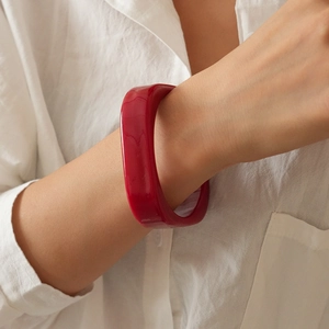 Detailed view of a wide chunky red resin bangle on a model wrist for a bold retro style