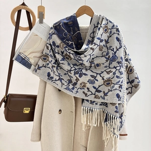 Close-up of beige jacquard shawl with blue vintage floral patterns and fringe details