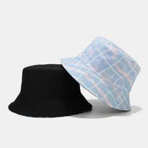 Detail of reversible graffiti plaid and black bucket hats showing cotton fabric texture