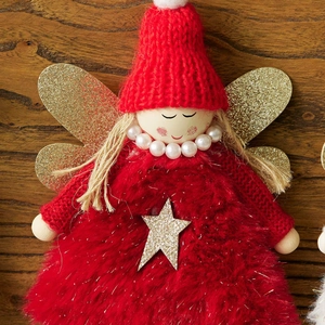 Handmade red knit Christmas angel tree topper with gold wings on wood background