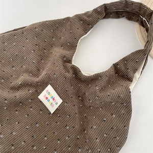 Macro shot of brown corduroy tote bag showing fine floral prints and woven label detail