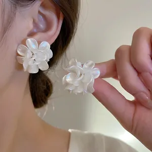 Boucles d'oreilles 3D en forme de fleurs blanches avec fini nacré portées