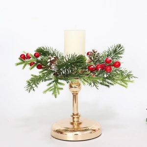 Close-up of golden metal candlestick with frost pine needles, red berries and beige candle