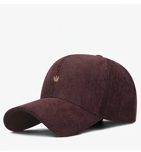Close-up of burgundy herringbone fabric baseball cap with a small gold crown emblem