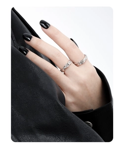 Close-up of minimalist silver couple rings with wavy texture and diamond accents on hand
