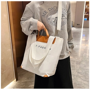 Detail of white canvas tote with brown leather handles and adjustable shoulder strap