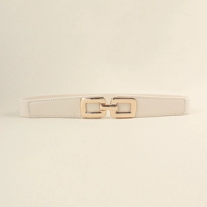 Close-up of interlocking gold buckle and cream elastic fabric on fashion waist belt