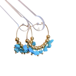 Bohemian stainless steel hoop earrings featuring turquoise stones and gold beads on a stand